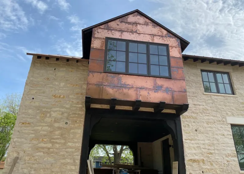Copper metal panel facade on a stone building for Skylight Installation in Gray